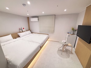 A hotel room with a large bed, a small table, a television, and a window with blinds. - Monolith Stay Hotel (Incheon)