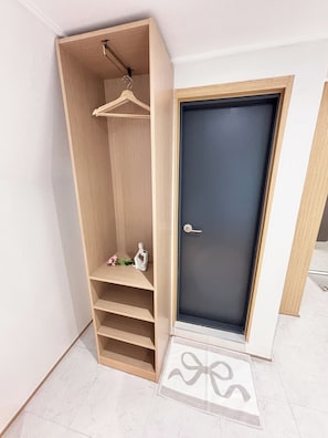 A room with a wooden wardrobe, a door, and a doormat with a bow design. - Monolith Stay Hotel (Incheon)
