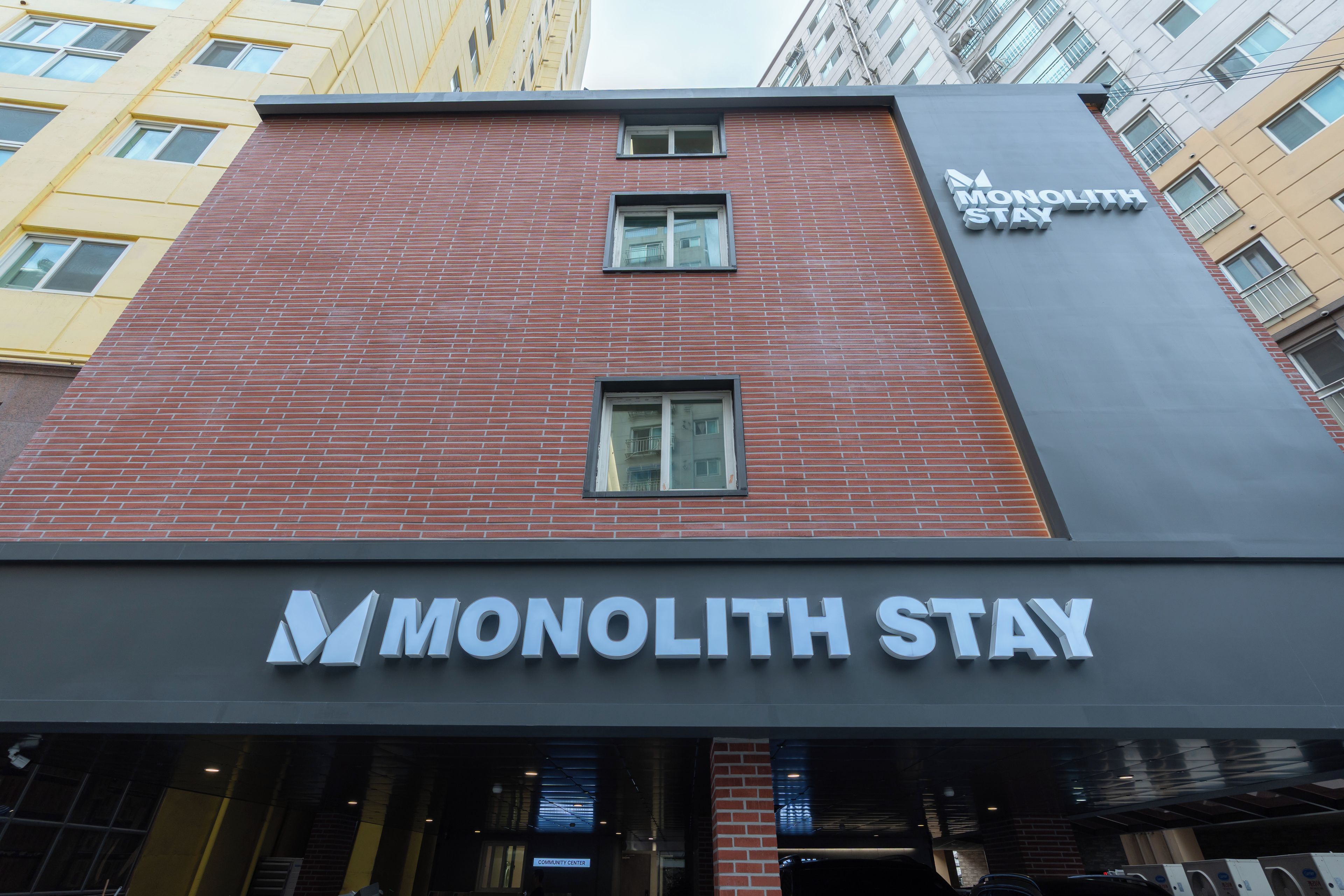 A building with a brick facade and a sign for Monolith Stay.
