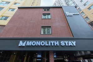 A building with a brick facade and a sign for Monolith Stay. - Monolith Stay Hotel (Incheon)