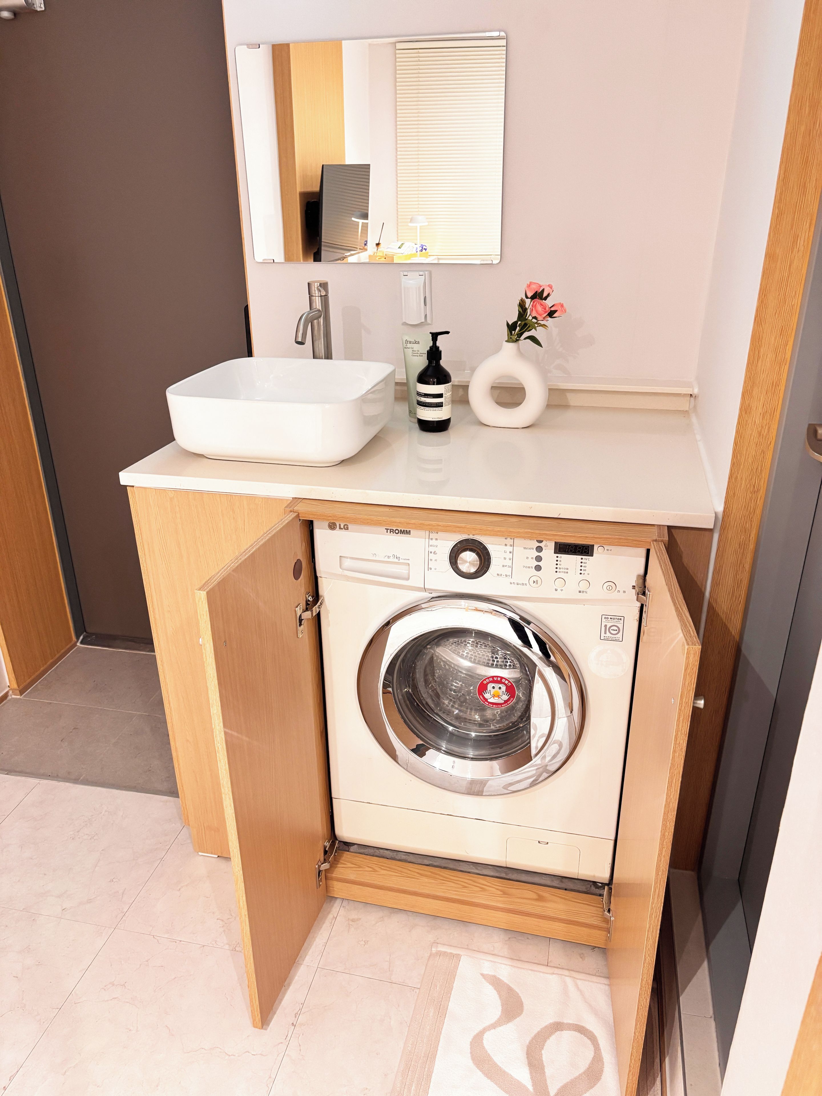 Une petite salle de bain comprenant un lavabo, un miroir et un lave-linge.