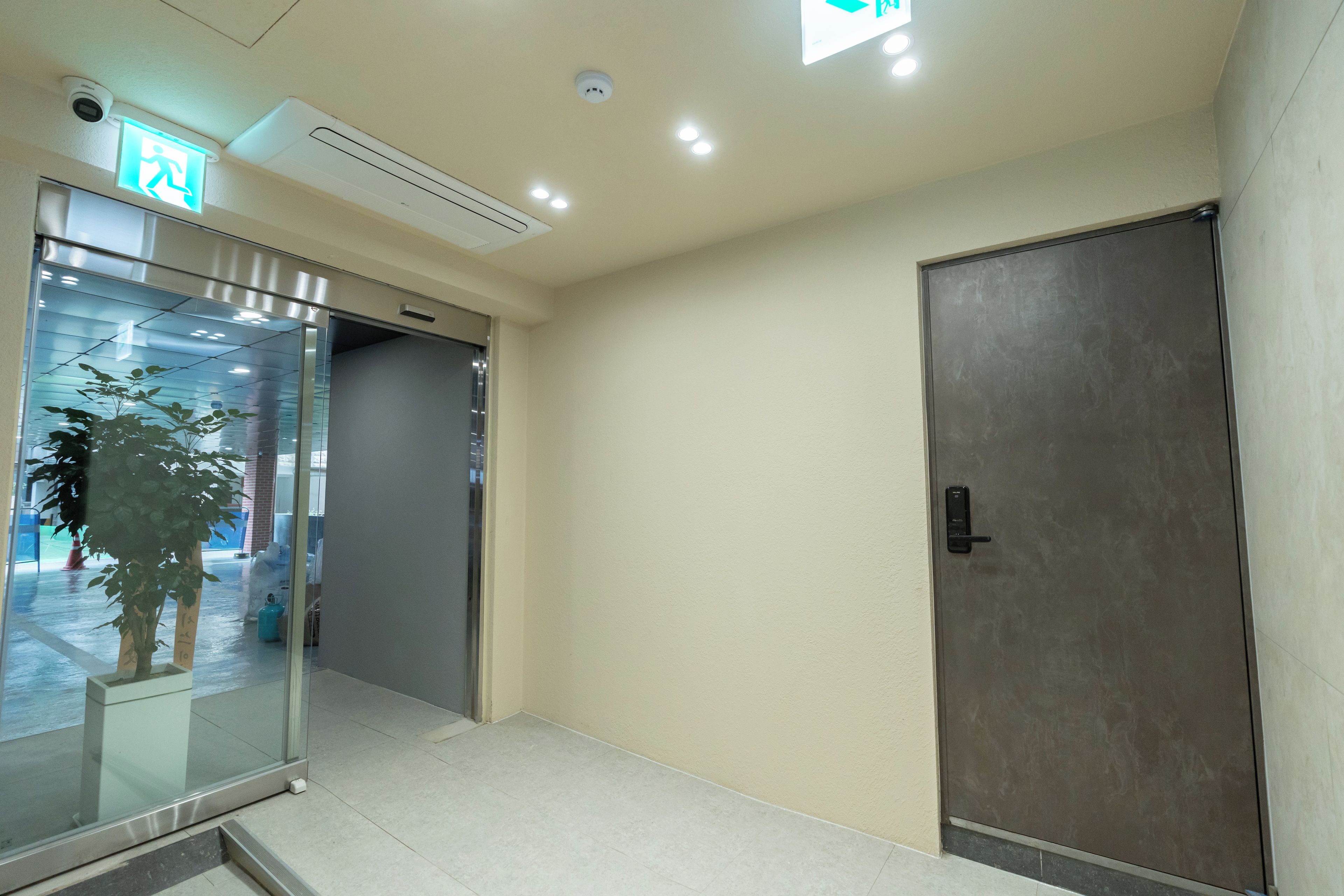 A hallway with a glass door entrance, a door with a handle, and a ceiling with recessed lighting.