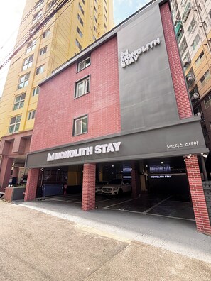 A hotel named Monolith Stay with a red brick facade and a grey upper section.