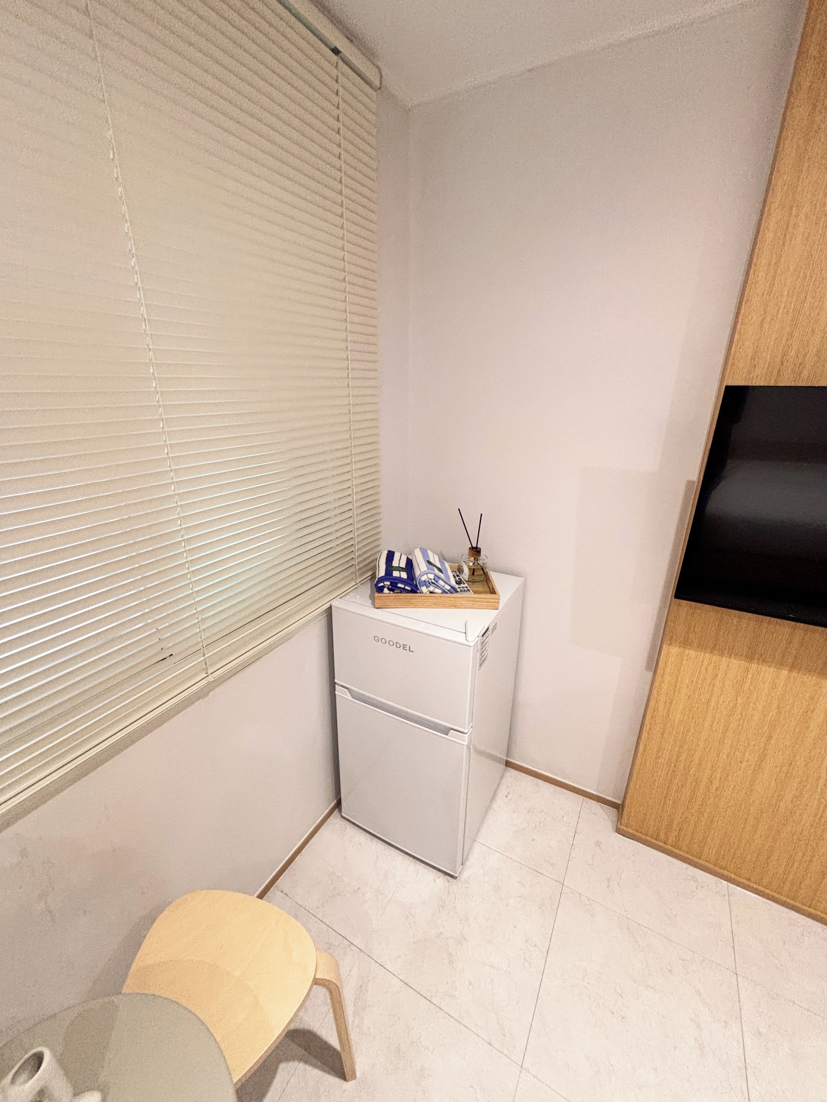 Une pièce de taille modeste, avec un réfrigérateur blanc, une petite table et un meuble en bois.
