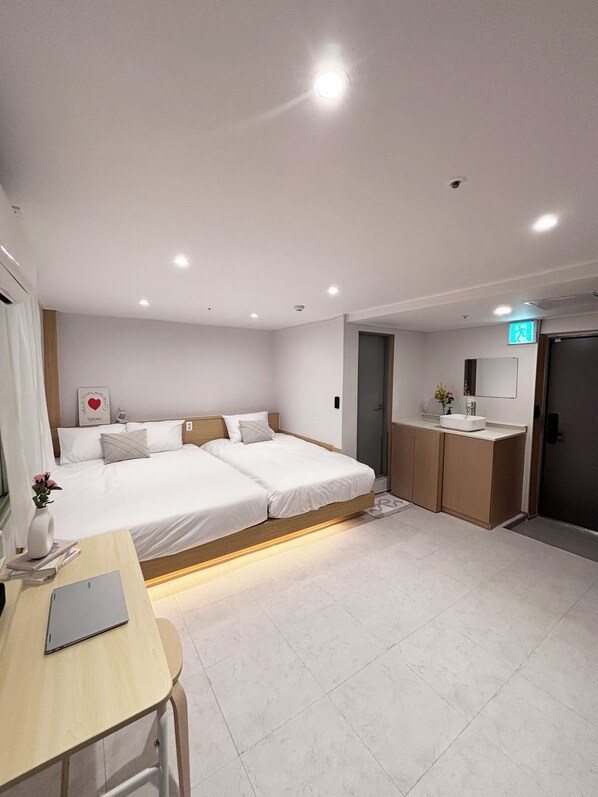 A modern bedroom with a bed, bedside table, and a small desk.