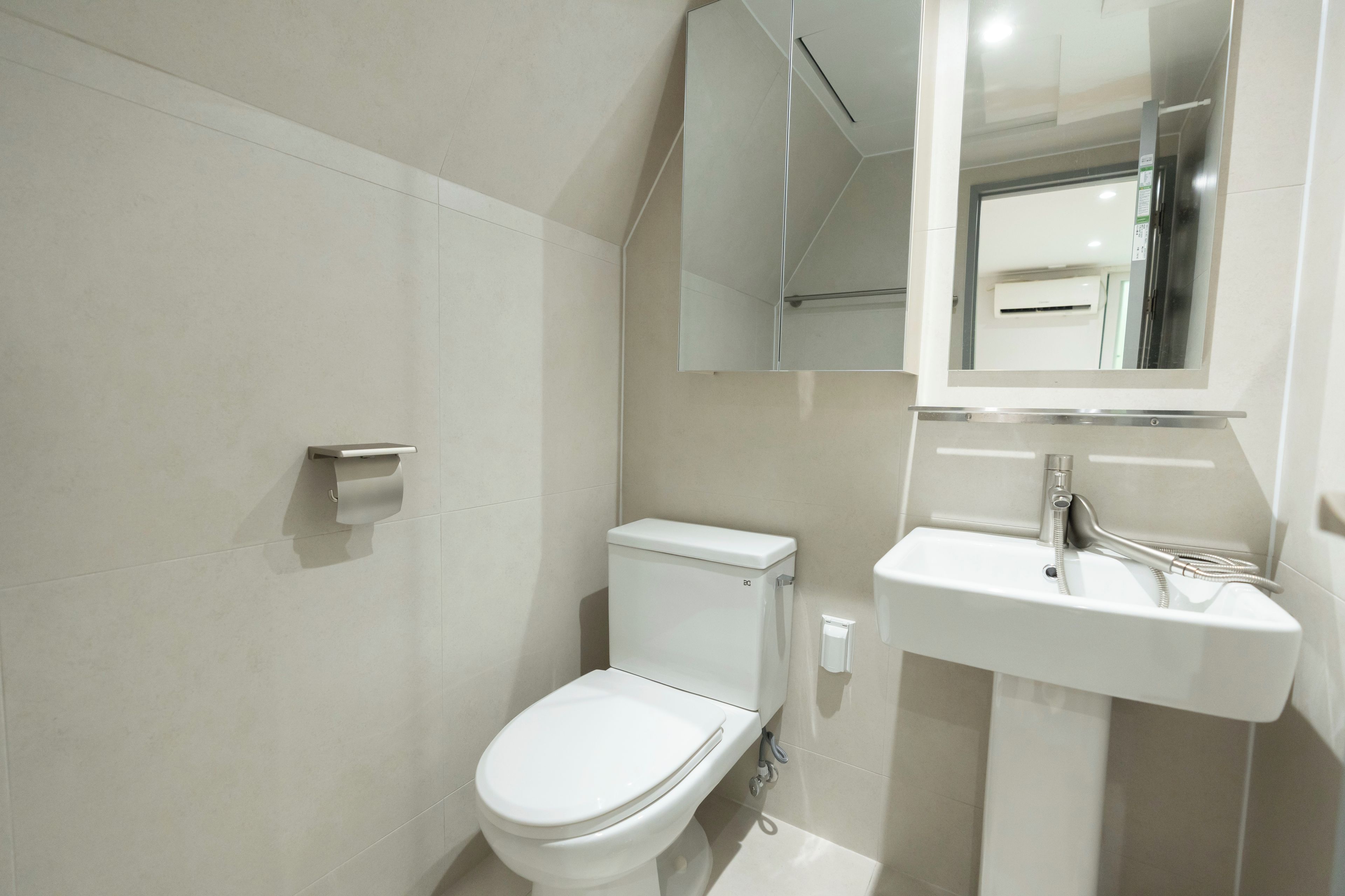 Un baño moderno con inodoro, lavamanos y espejo.