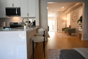 A modern kitchen with a central island, bar stools, and a dining area with a sofa and chairs. - Modern 4 bedroom house in Milton (Milton)