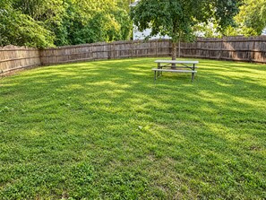 A backyard with a wooden fence, a picnic table, and a tree. - Spacious Family Retreat Near Stone Mountain Park and Lake Lanier Island (Snellville)