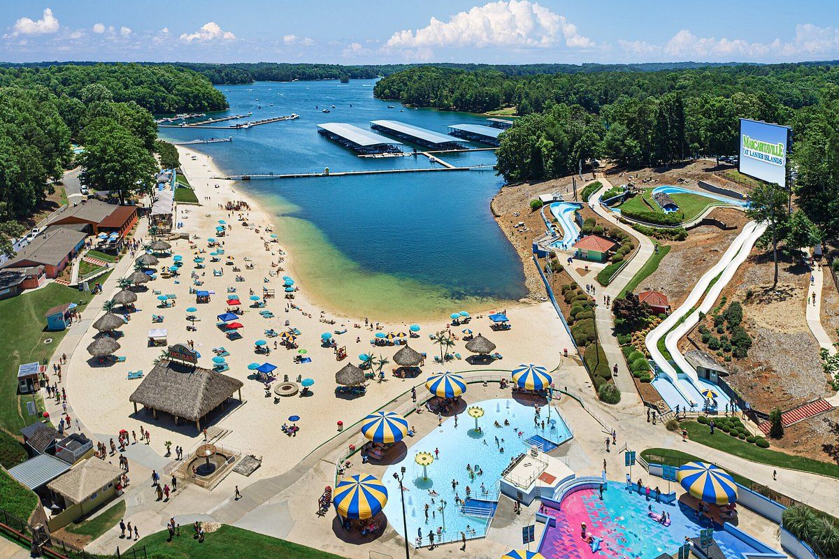 A beach resort with a swimming pool, water slides, and a beach area with umbrellas.