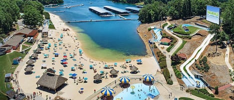A beach resort with a swimming pool, water slides, and a beach area with umbrellas.