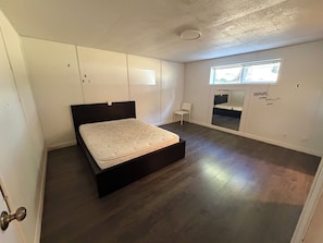 Een slaapkamer met een bed, een raam en een deur.