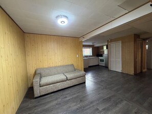 Ein Zimmer mit einer Couch, Holzwänden, einer Küchenzeile und einer Schiebetür.