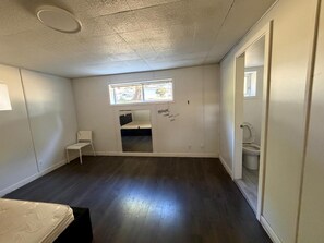 Ein Zimmer mit einem Etagenbett, einem kleinen Fenster, einer Toilette und einem Stuhl.