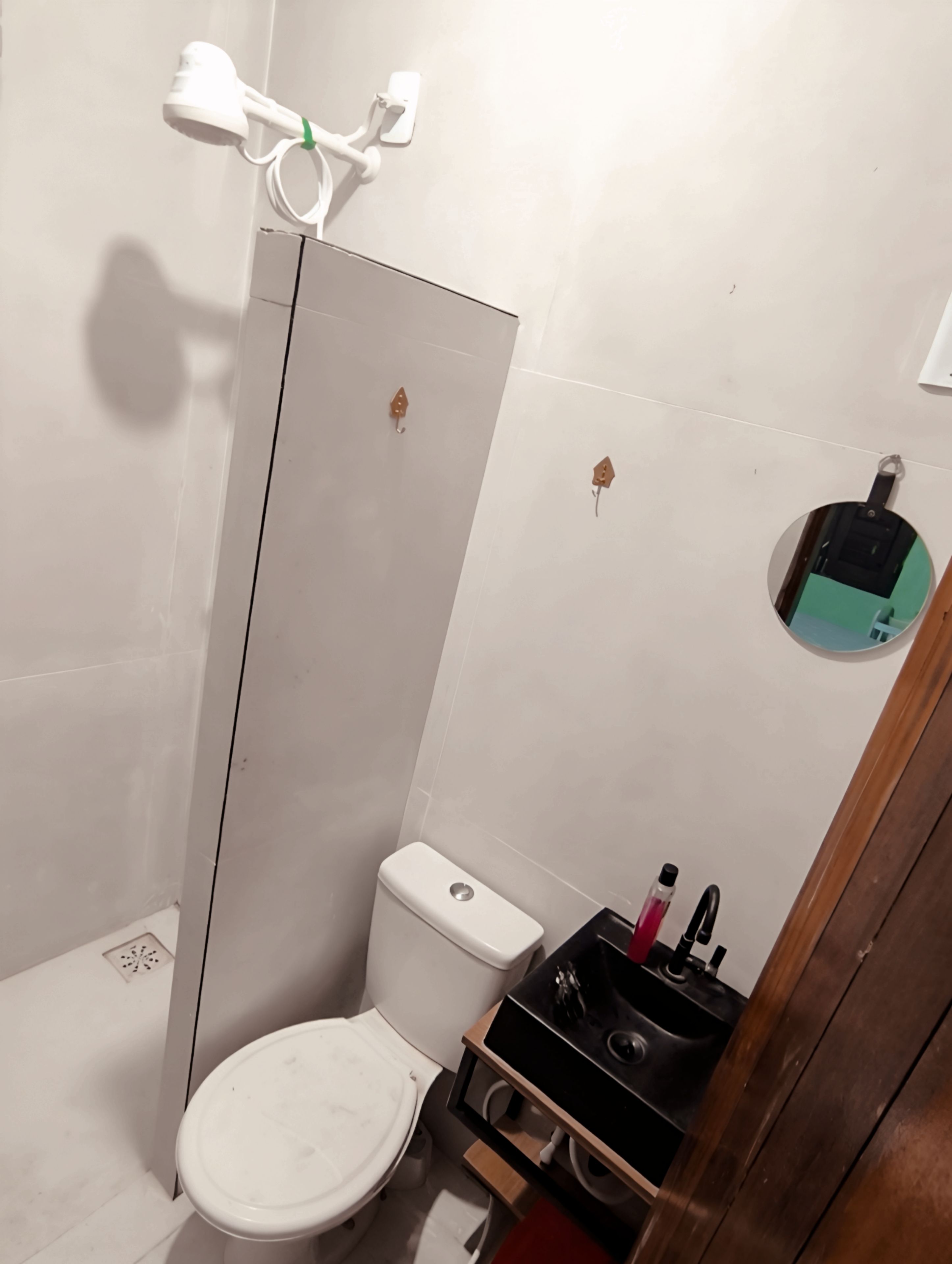 A small bathroom with a toilet, a shower, and a mirror.