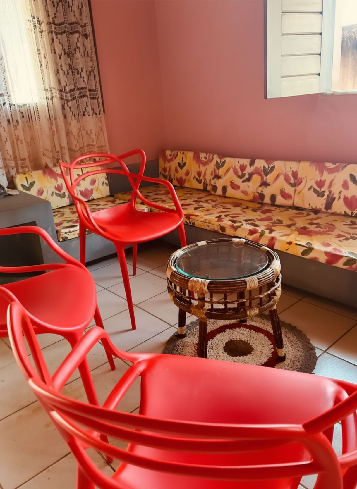 Quarto com sofá, duas cadeiras vermelhas e uma pequena mesa redonda.