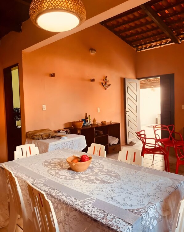 Un comedor con una mesa dispuesta para dos, un frutero y una silla roja.