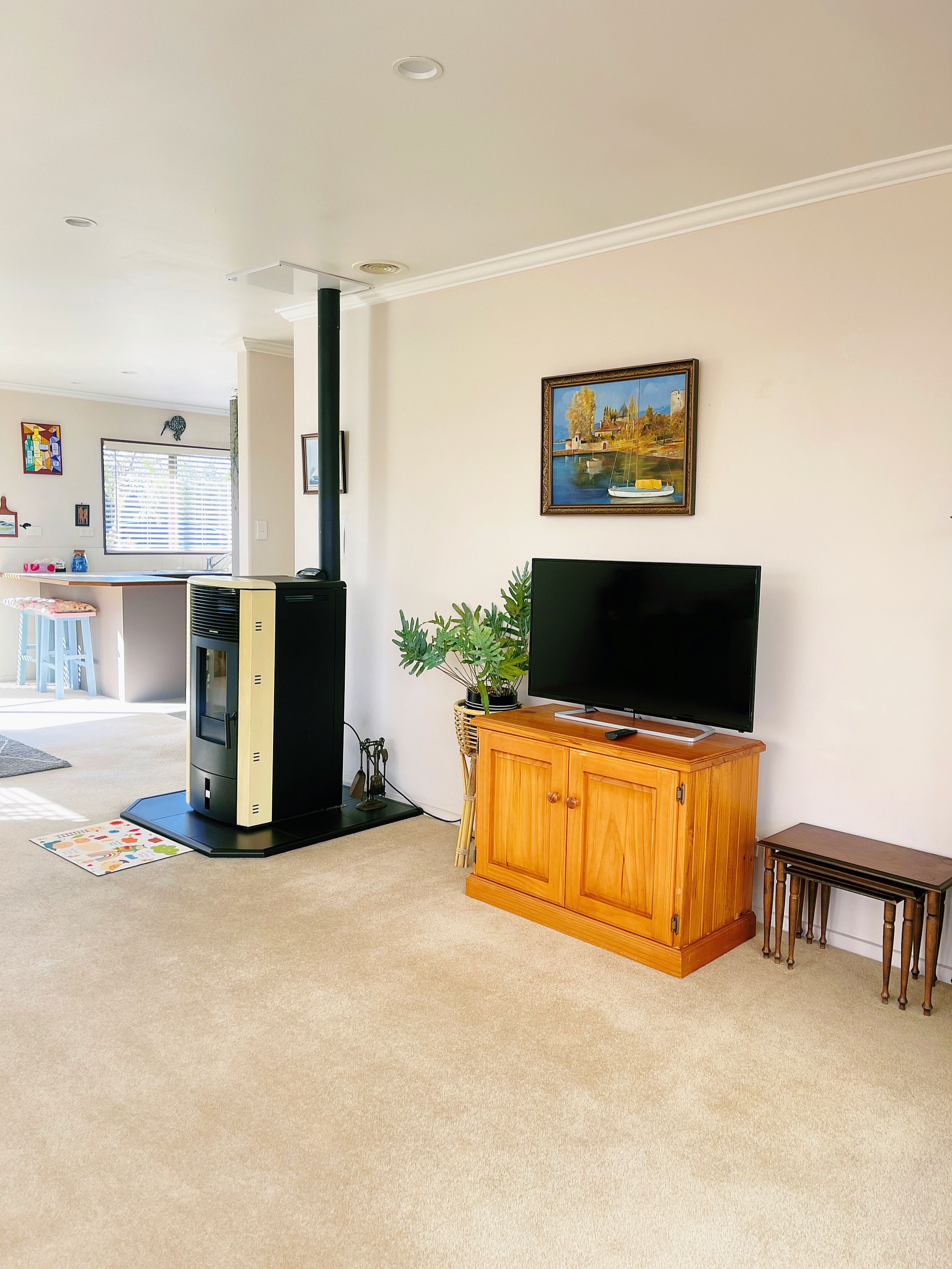 Una sala de estar con televisión sobre un mueble de madera, chimenea y un cuadro en la pared.