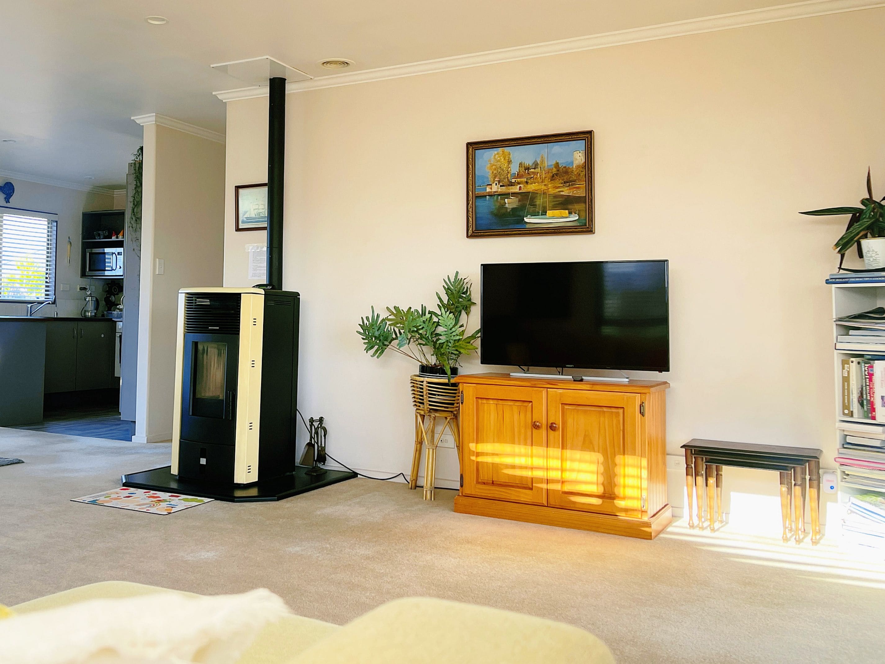 Una sala de estar con televisor de pantalla plana, chimenea, estantería y un cuadro en la pared.