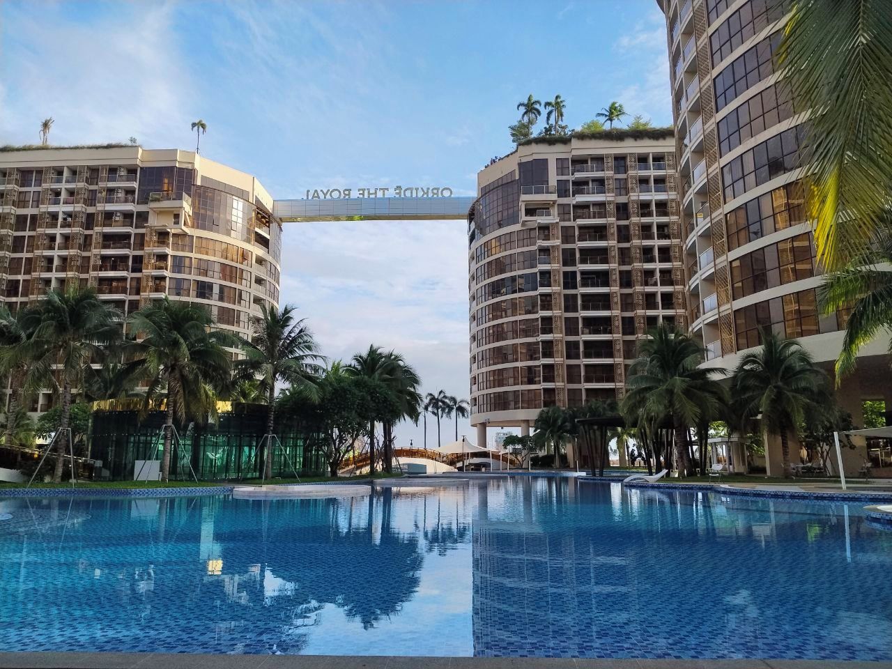 A hotel with a central pool, palm trees, and a sign reading 'ORANGE THE ROYAL'.