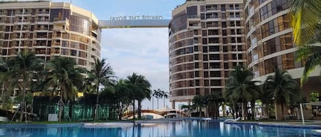 A hotel with a central pool, palm trees, and a sign reading 'ORANGE THE ROYAL'.
