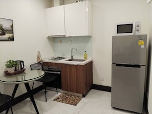 A compact kitchen with a refrigerator, microwave, sink, and stove. - 
The Royal minimum condo Orkide Phnom Penh with AC and gym (Phnom Penh)