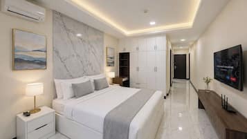 A modern bedroom with a large bed, bedside tables, a TV, and a marble wall.