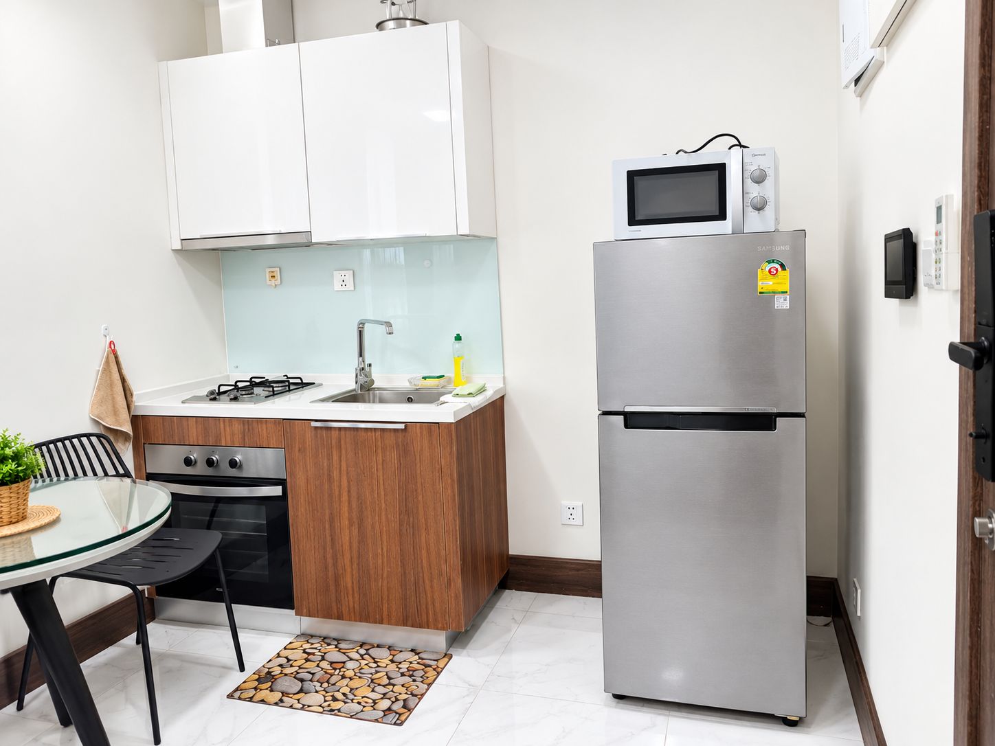 A compact kitchen with a gas stove, a microwave, and a stainless steel refrigerator.