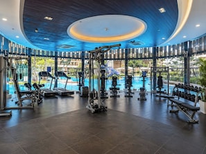A gym with exercise equipment, a swimming pool, and large windows. - 
The Royal minimum condo Orkide Phnom Penh with AC and gym (Phnom Penh)