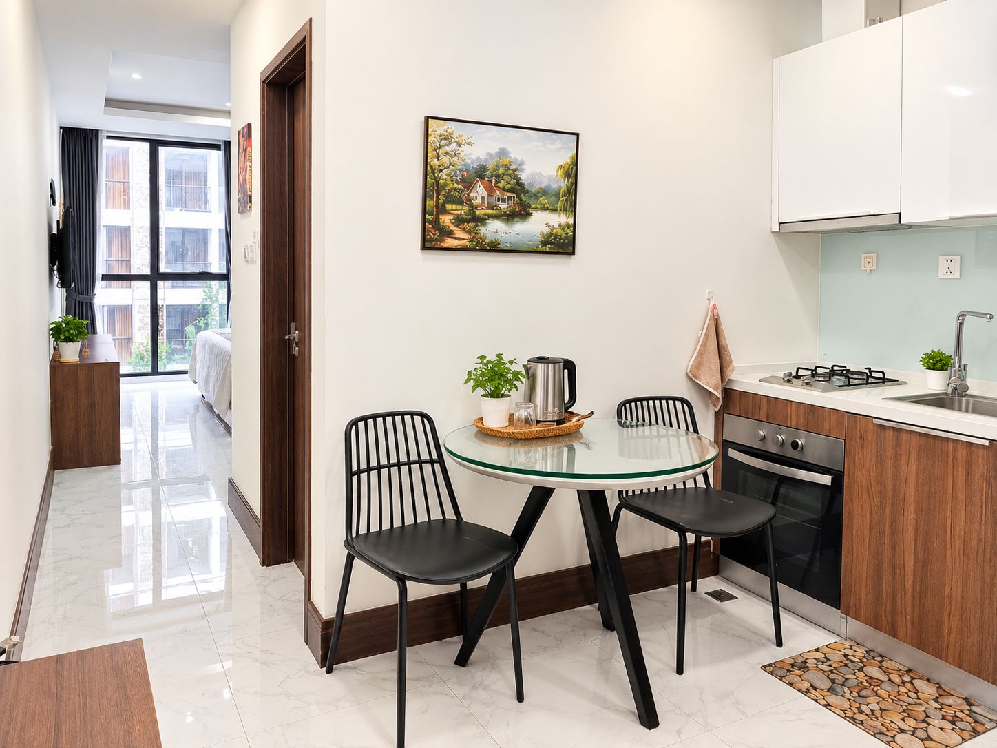 A modern kitchen with a dining area, a painting on the wall, and a view to the outside.