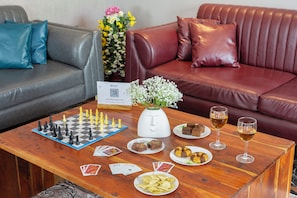 Een woonkamer met een schaakbord, snacks, drankjes en een bloemenvaas.
