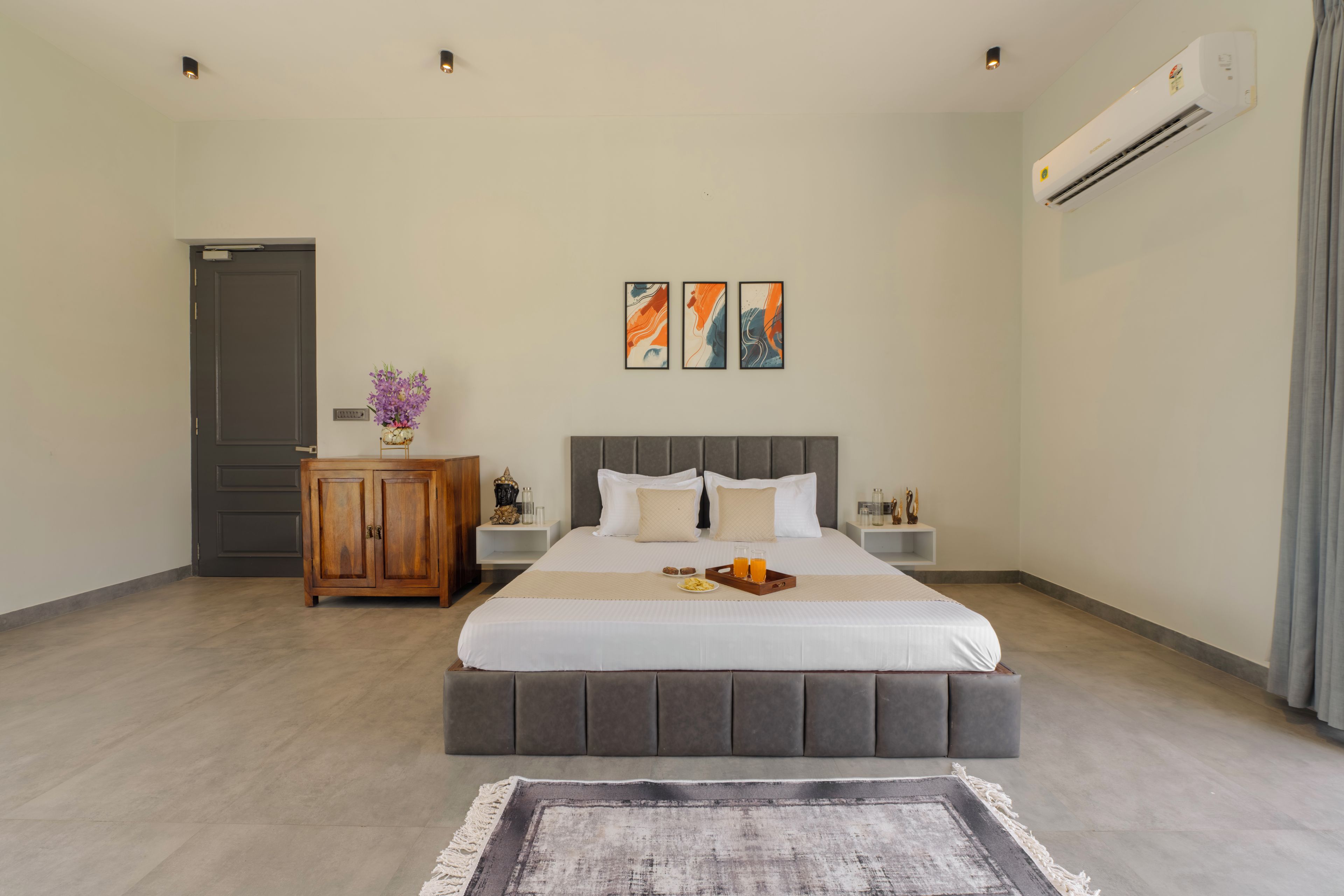 Une chambre d’hôtel avec un lit, des tables de chevet, une armoire et des œuvres d’art accrochées au mur.