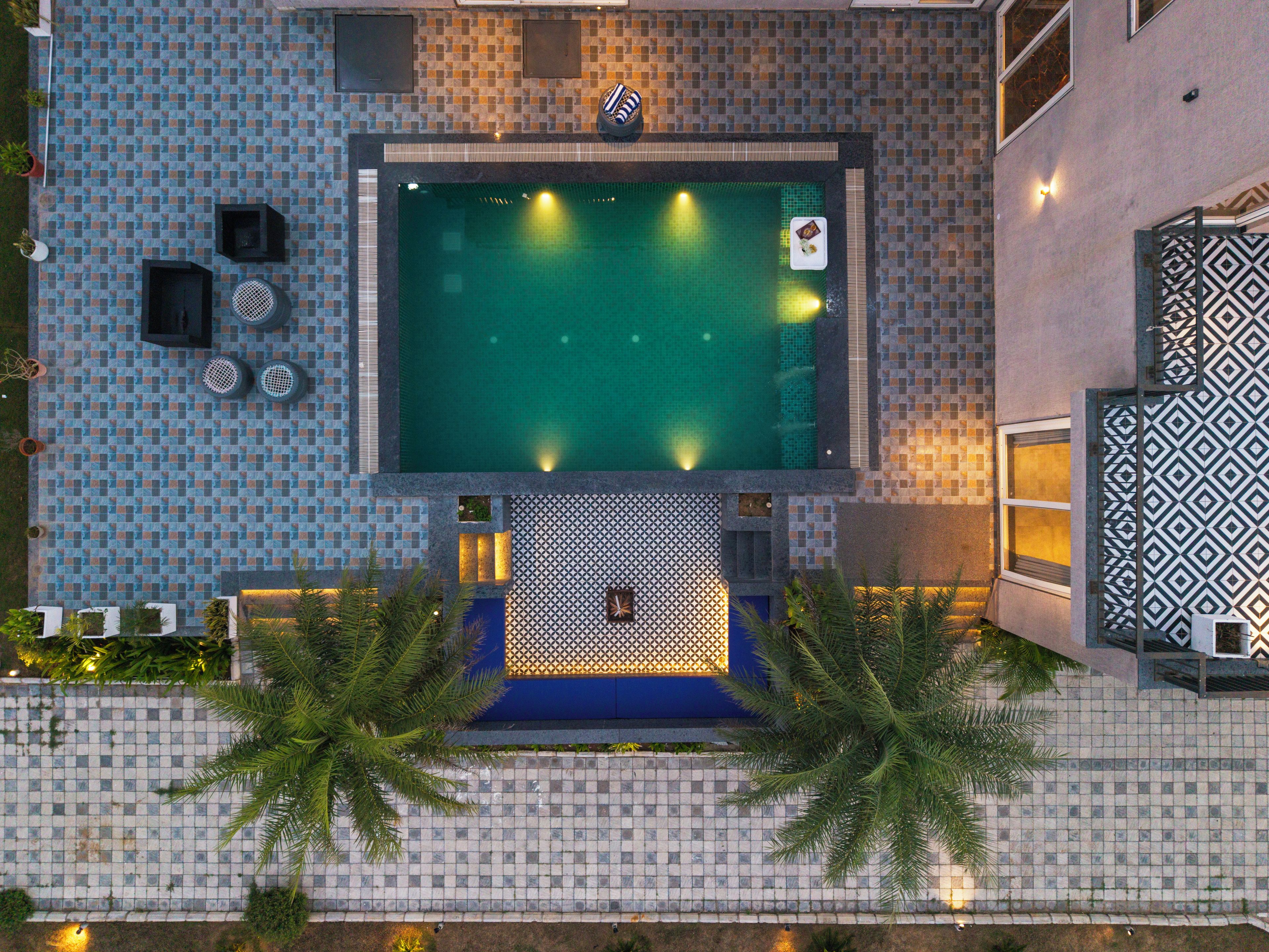 An aerial view of a hotel with a swimming pool, tiled walls, and outdoor seating.