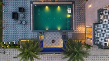 An aerial view of a hotel with a swimming pool, tiled walls, and outdoor seating.