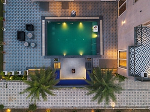 Vue aérienne d'un hôtel doté d'une piscine, de murs recouverts de carreaux et d'un espace de détente extérieur.