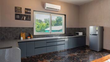 A modern kitchen with a large window, a built-in air conditioner, and a refrigerator.