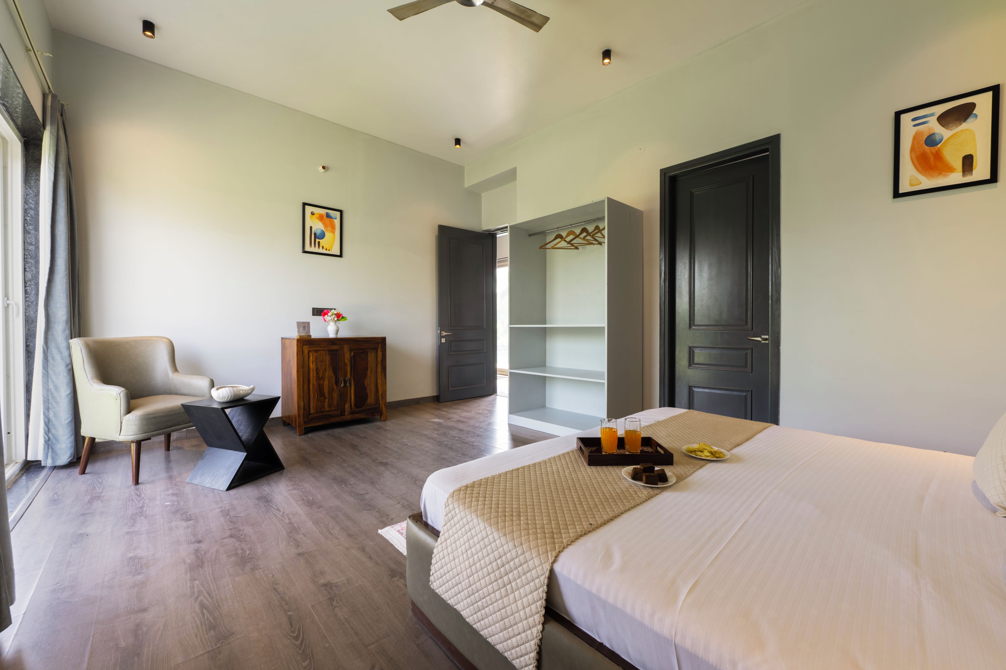 A hotel room with a bed, a chair, a wardrobe, and a desk.