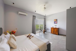 Een hotelkamer met een bed, een kleintje tafeltje met drankjes en gebak, een balkon met stoelen en een houten kast.