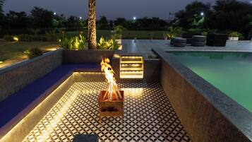 A poolside area with a fire feature, seating, and a tiled floor.