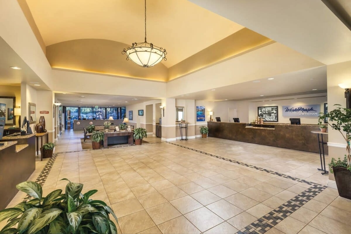 A spacious lobby with a reception desk, seating area, and a chandelier.