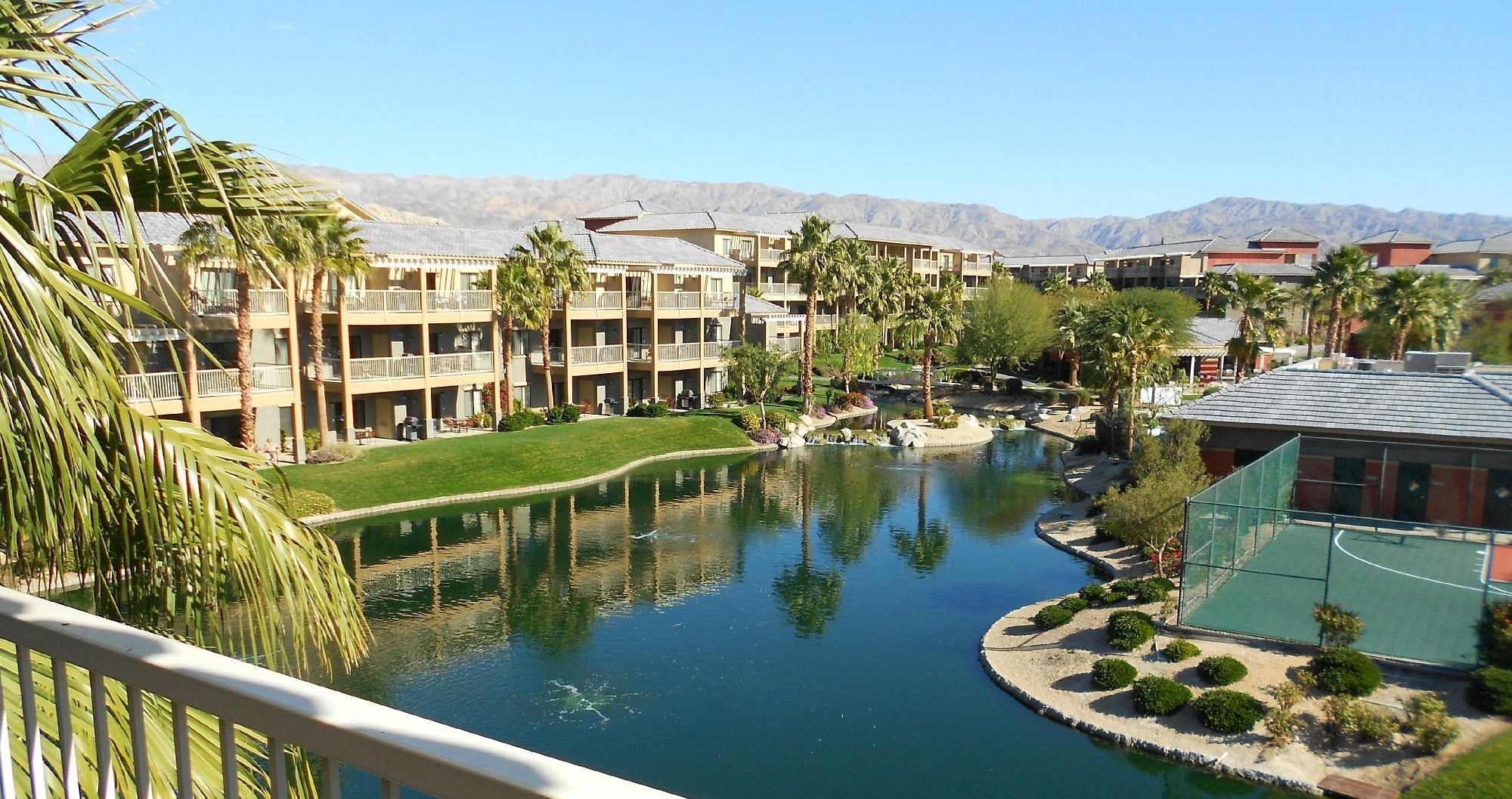 A hotel with multiple balconies, a central water feature, and a mountainous backdrop.