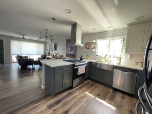 Una cocina moderna con una isla central, electrodomésticos de acero inoxidable y un área de comedor con sofá y sillas.