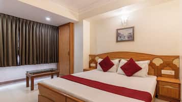 Quarto de hotel com cama de madeira, mesa de cabeceira, luminária e um quadro na parede, além de uma janela com cortinas.