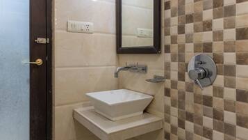A bathroom with a white sink, a mirror, and a tiled wall.