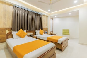 A hotel room with two beds, a mirror, a green chair, and a ceiling fan.