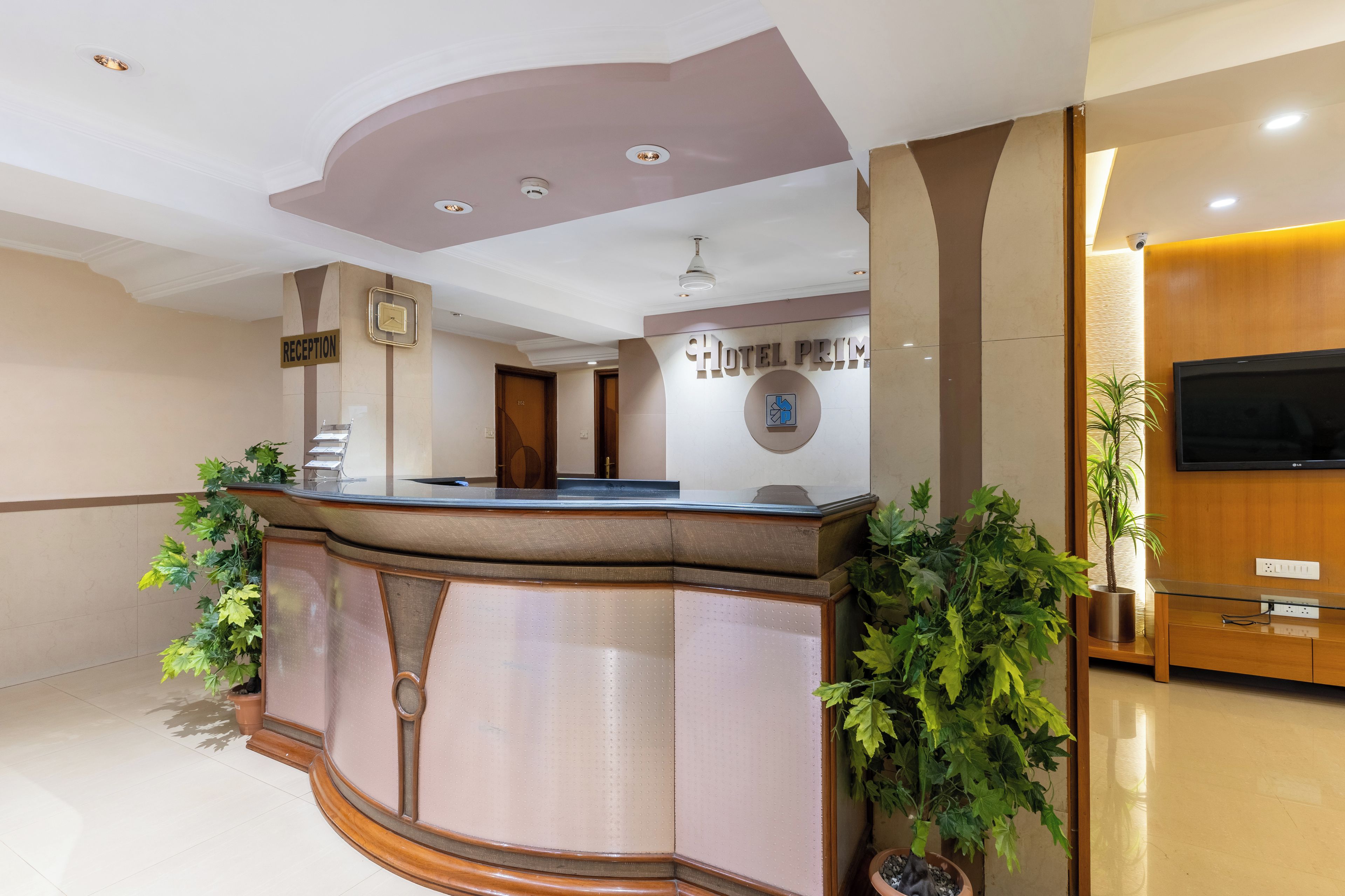 A reception desk with a clock, a reception sign, and a wall-mounted sign for the hotel.