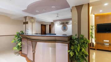 A reception desk with a clock, a reception sign, and a wall-mounted sign for the hotel.