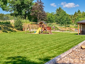A well-maintained grassy area with a wooden play structure and a small building. - George 05 by Interhome (Kovářská)