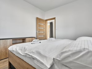 A bedroom with a wooden bed, a nightstand, and a mirror. - George 05 by Interhome (Kovářská)