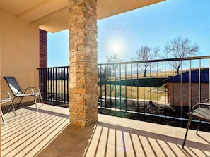 A balcony with a stone pillar, metal chairs, and a view of a rural landscape. - George 05 by Interhome (Kovářská)