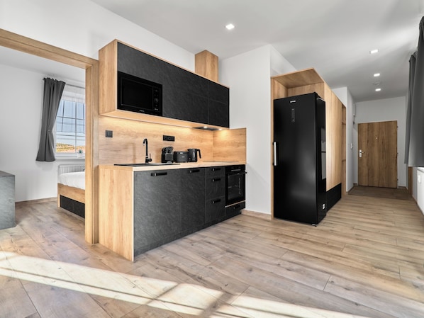 Una cocina moderna con microondas integrado, horno y refrigerador negro.